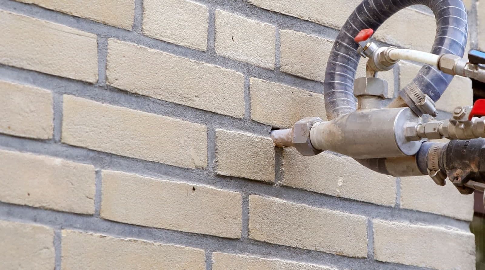 Monteur spuit isolatiemateriaal in de spouwmuur van een woning